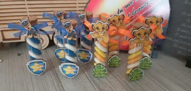 Bocaux de bonbons en spirale avec rubans bleu et orange, décor animalier, posés sur table en bois.