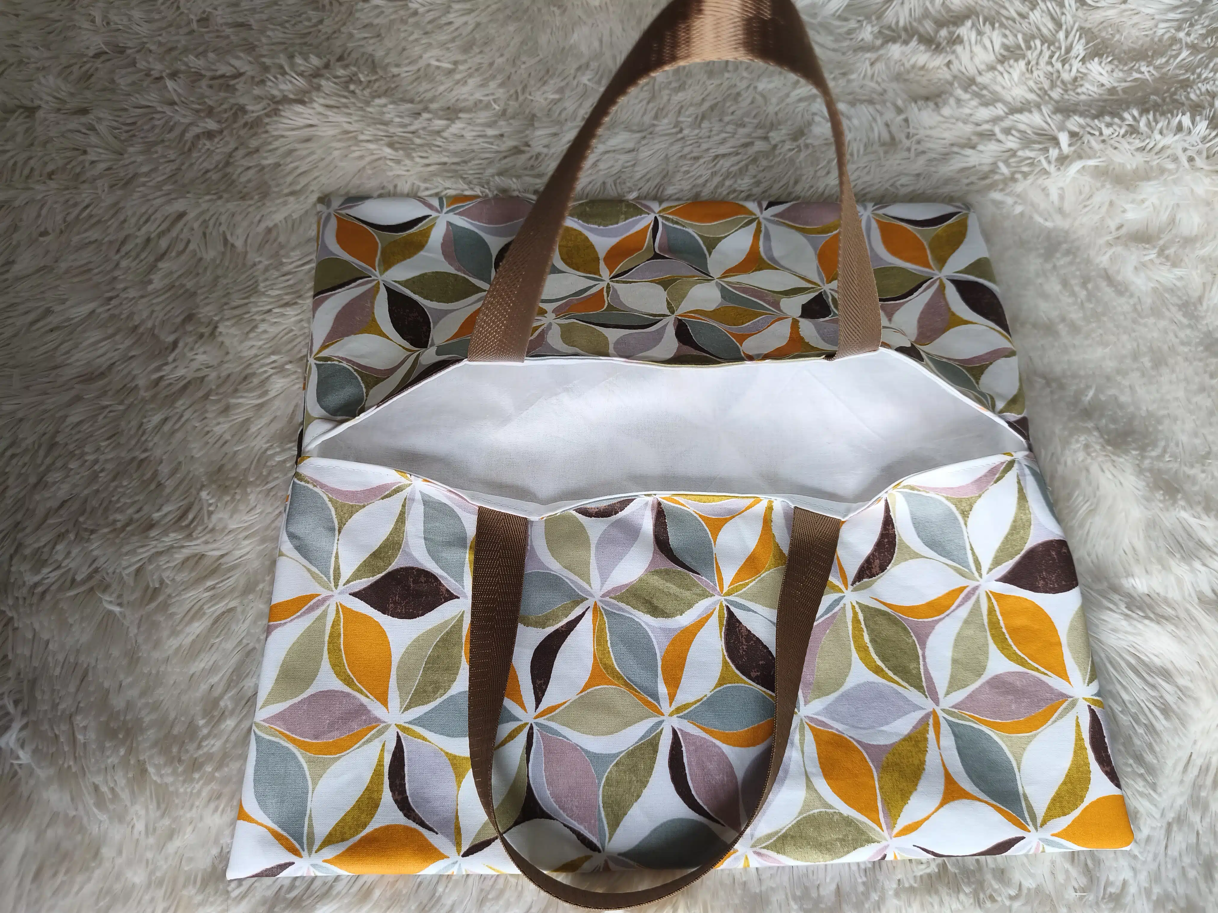 Sac à tarte 3 Sac cabas en tissu à motifs, anses marron, intérieur blanc visible, posé sur une surface texturée.