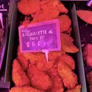 Aiguillettes de poulet panées en vitrine, étiquette de prix visible, volaille prête à cuire.