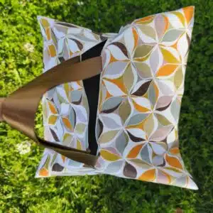 Sac cabas à motifs avec anses marron posé sur l'herbe verte, vu du dessus.