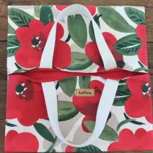 Sac cabas en tissu à fleurs rouges "Safilea" avec anses blanches, posé sur une surface en bois.