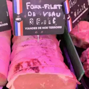 Faux filet de veau tranché en vitrine, étiquette de prix visible chez le boucher.