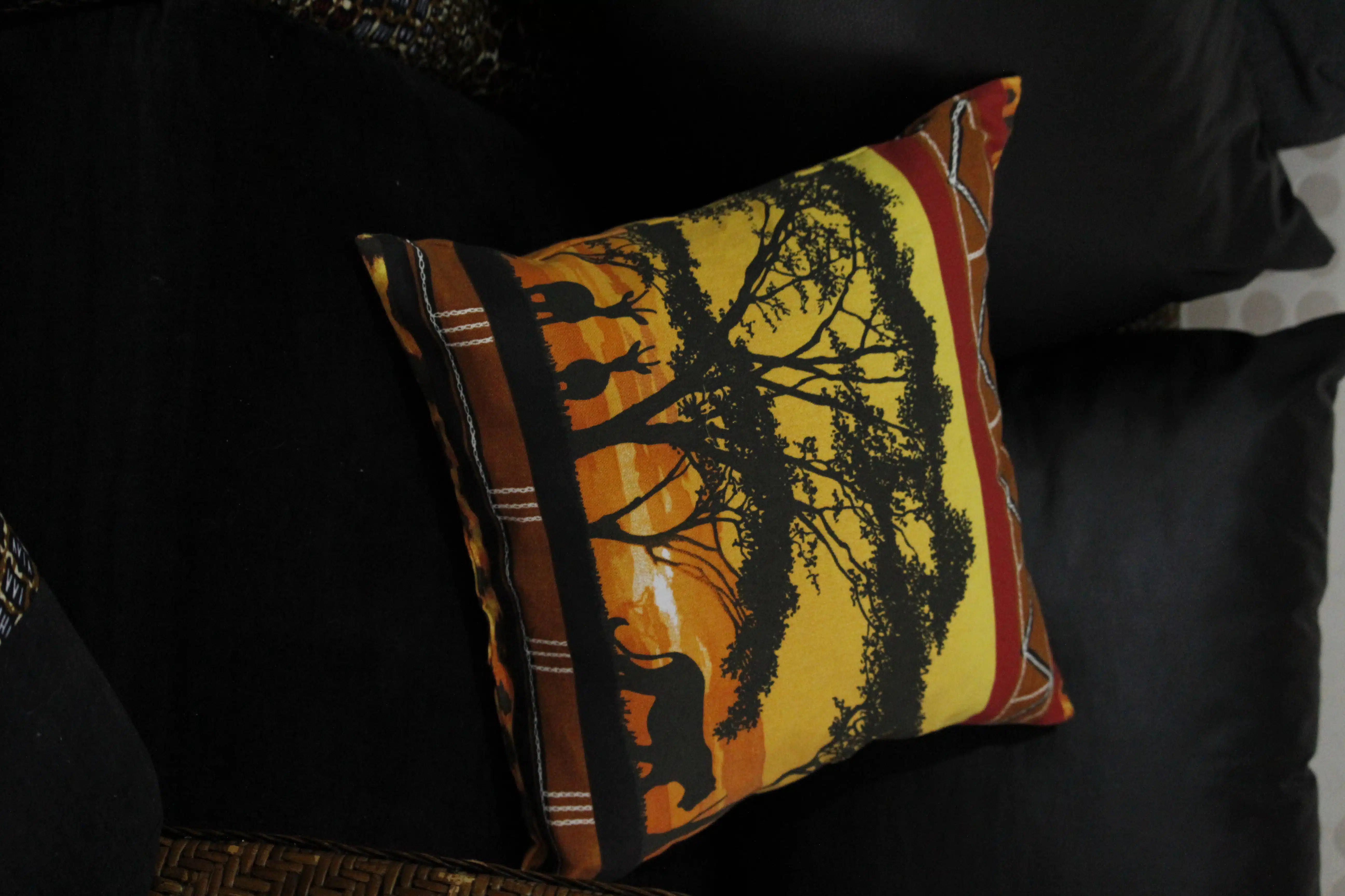 Coussin décoratif « Savane » en toile de coton 4 Coussin décoratif savane coucher de soleil avec arbres, cerf, gros félin sur canapé noir.