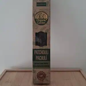 Boîte d’encens Organic Garden Patchouli posée sur un support en bois devant un mur blanc, produits naturels.