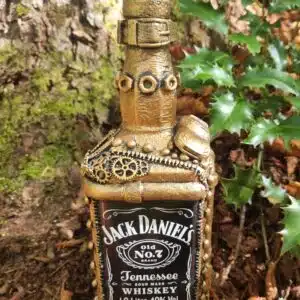 Accueil 14 Une bouteille de whisky de style Jack Daniels, de style steampunk doré, posée au sol, entourée de plantes vertes.
