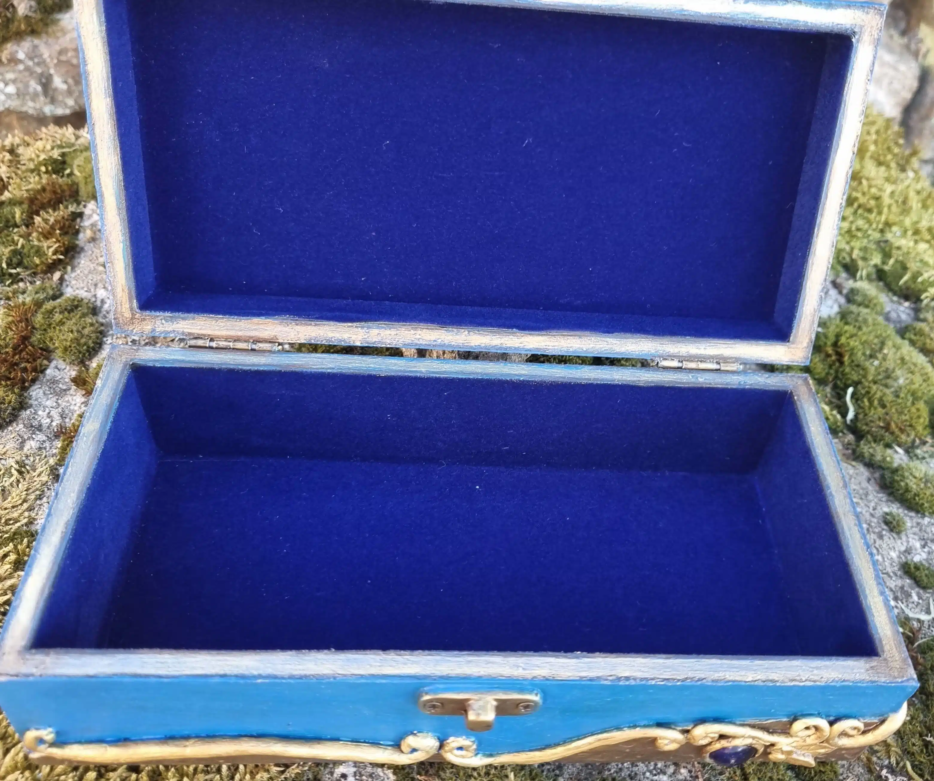Coffret décoratif bleu & or – Cristaux – Pièce unique artisanale 12 Boîte en bois aux finitions dorées et à l'intérieur en velours bleu, posée sur une pierre recouverte de mousse.