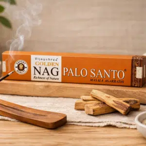 Un bâton de Palo Santo allumé à côté d’une boîte d’encens Vijayshree Golden Nag.