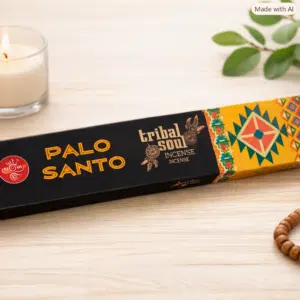 Accueil 10 Boîte d’encens Tribal Soul Palo Santo posée sur une table, accompagnée d’une bougie, de feuilles vertes et de perles en bois.