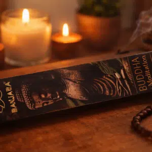 Accueil 11 Boîte d’encens en forme de Bouddha en bois, avec des bougies allumées et un bracelet de perles posés à côté.
