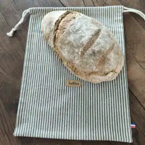 Accueil 12 Pain au levain croustillant posé sur un sac en toile rayée de la marque Safilea.